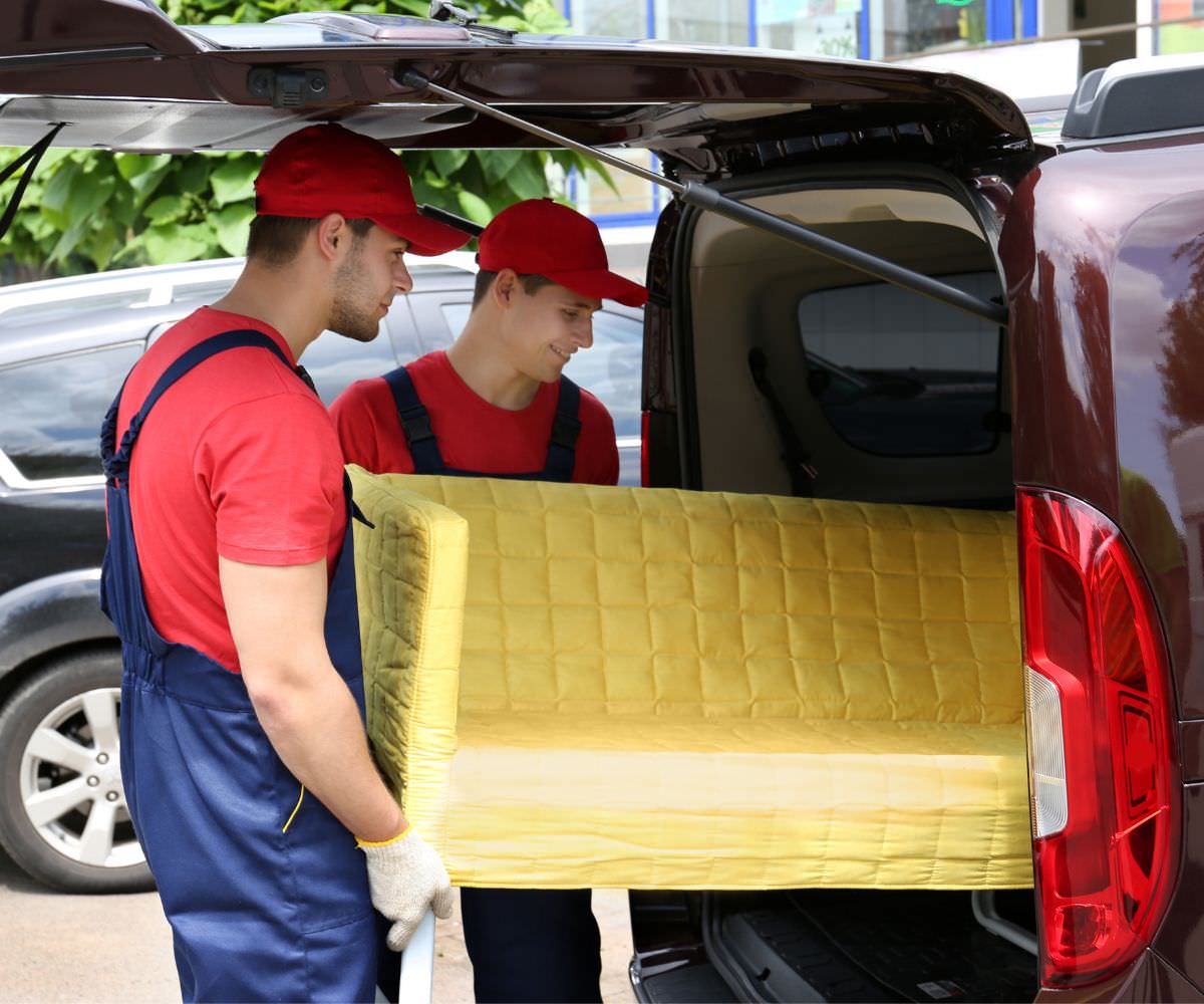 Umzugshelfer laden ein gelbes Sofa in einen Transporter – Preiswert umziehen Heidenheim