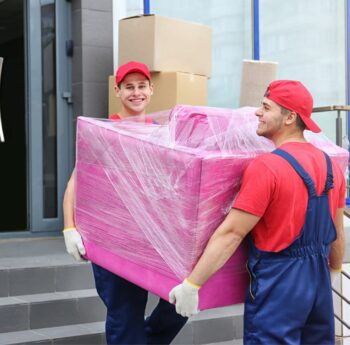 Umzug in Heidenheim Zwei Umzugshelfer tragen ein in Folie gepacktes Möbelstück – Umzug in Heidenheim